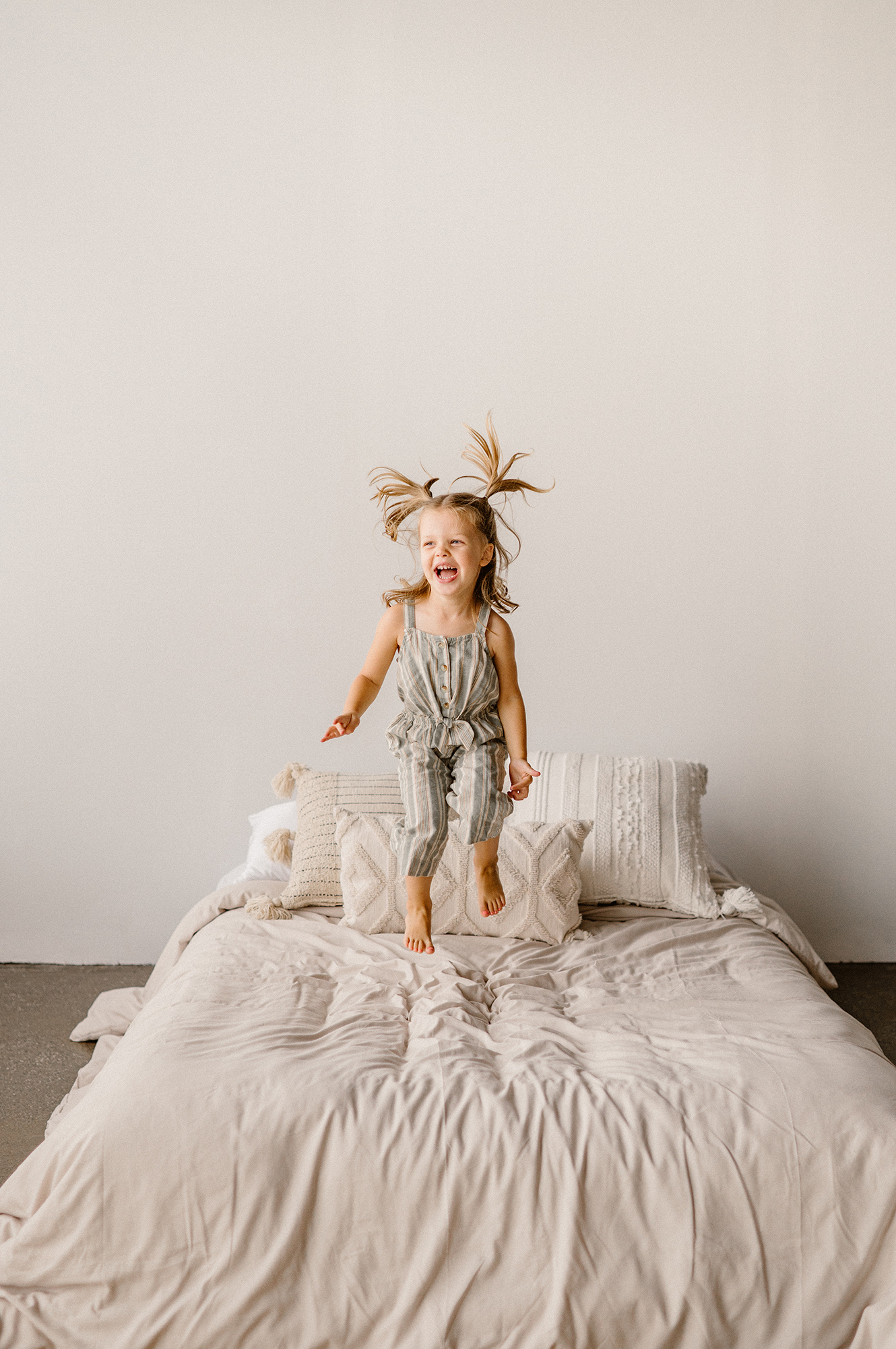 Windsor Ontario Family Photographer, little girl jumping on bed at Carrie J.s Studio