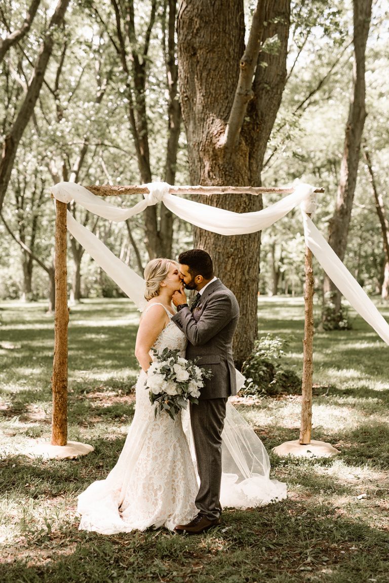 Couple kissing underneath wedding arch Sprucewood Winery Wedding