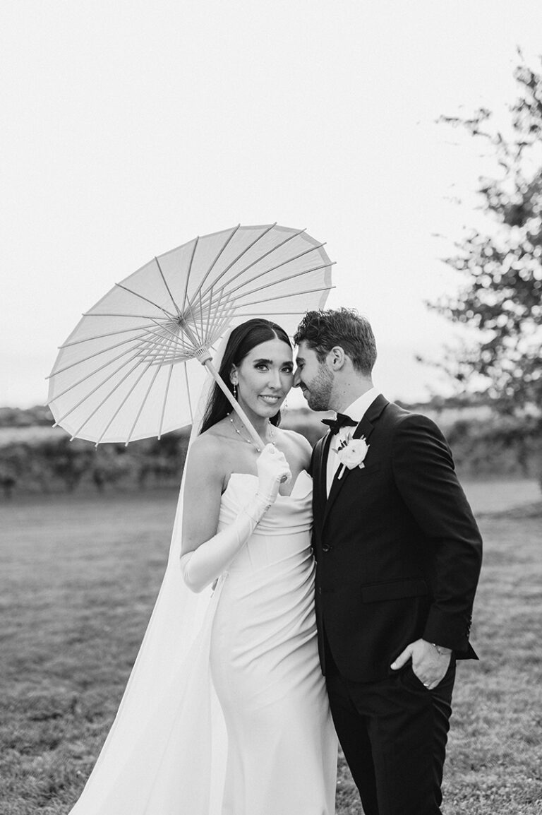 Bride and groom using paper umbrella for photos